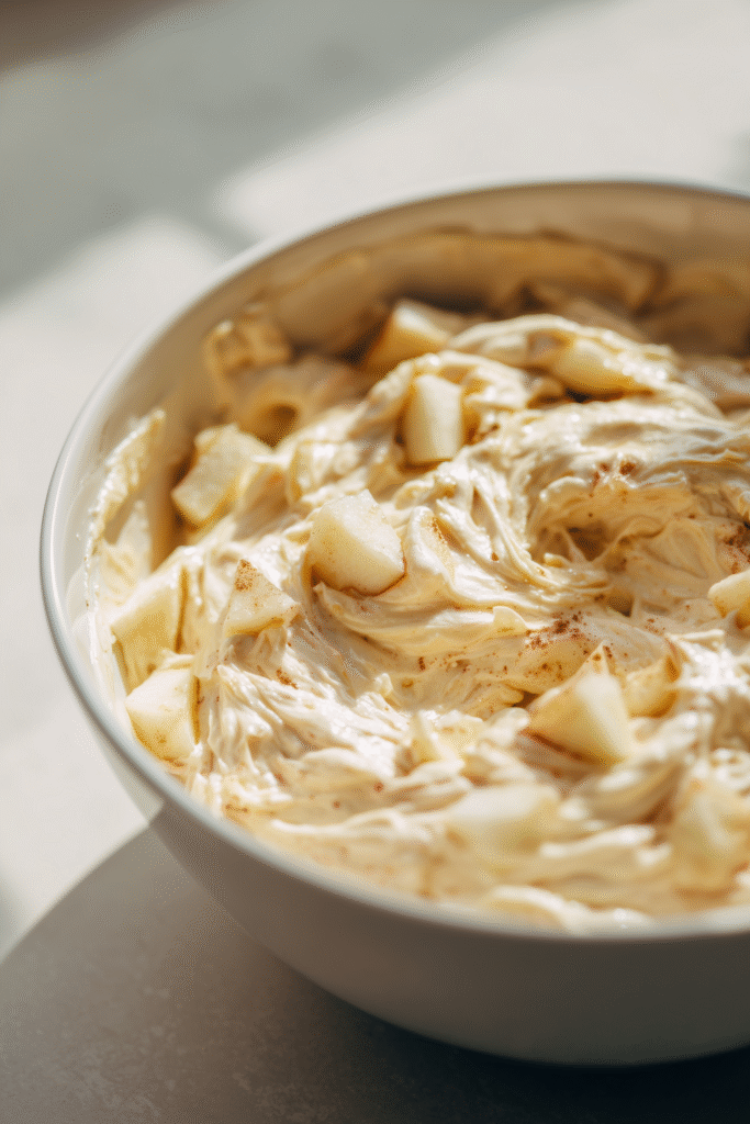Bowl of Apple Muffins batter with visible apple chunks and cinnamon, ready for baking.