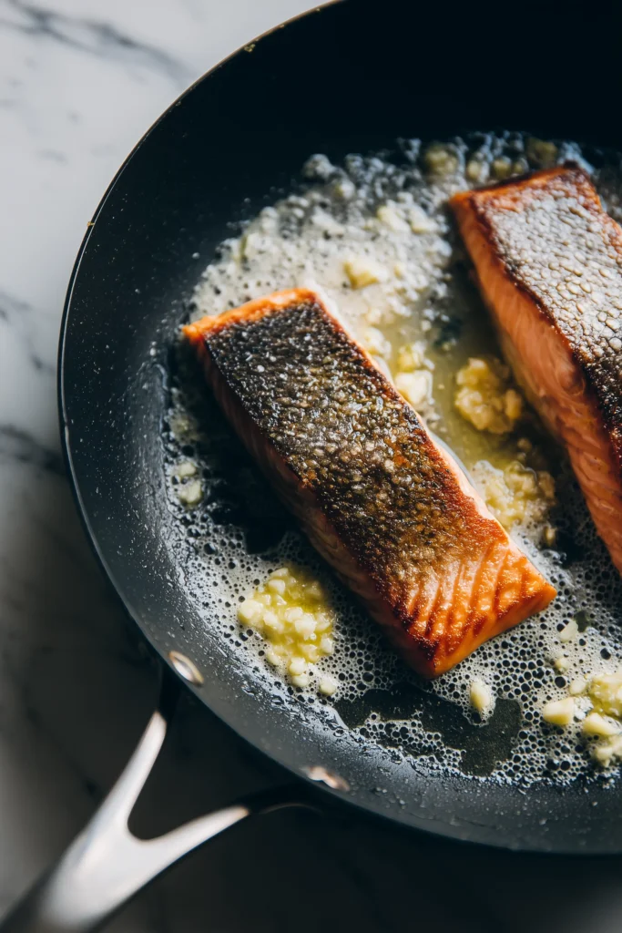 Creamy Cajun Salmon Pasta 3 Skillet with golden brown salmon and the start of the Creamy Cajun Salmon Pasta sauce, showing real textures and vibrant colors.