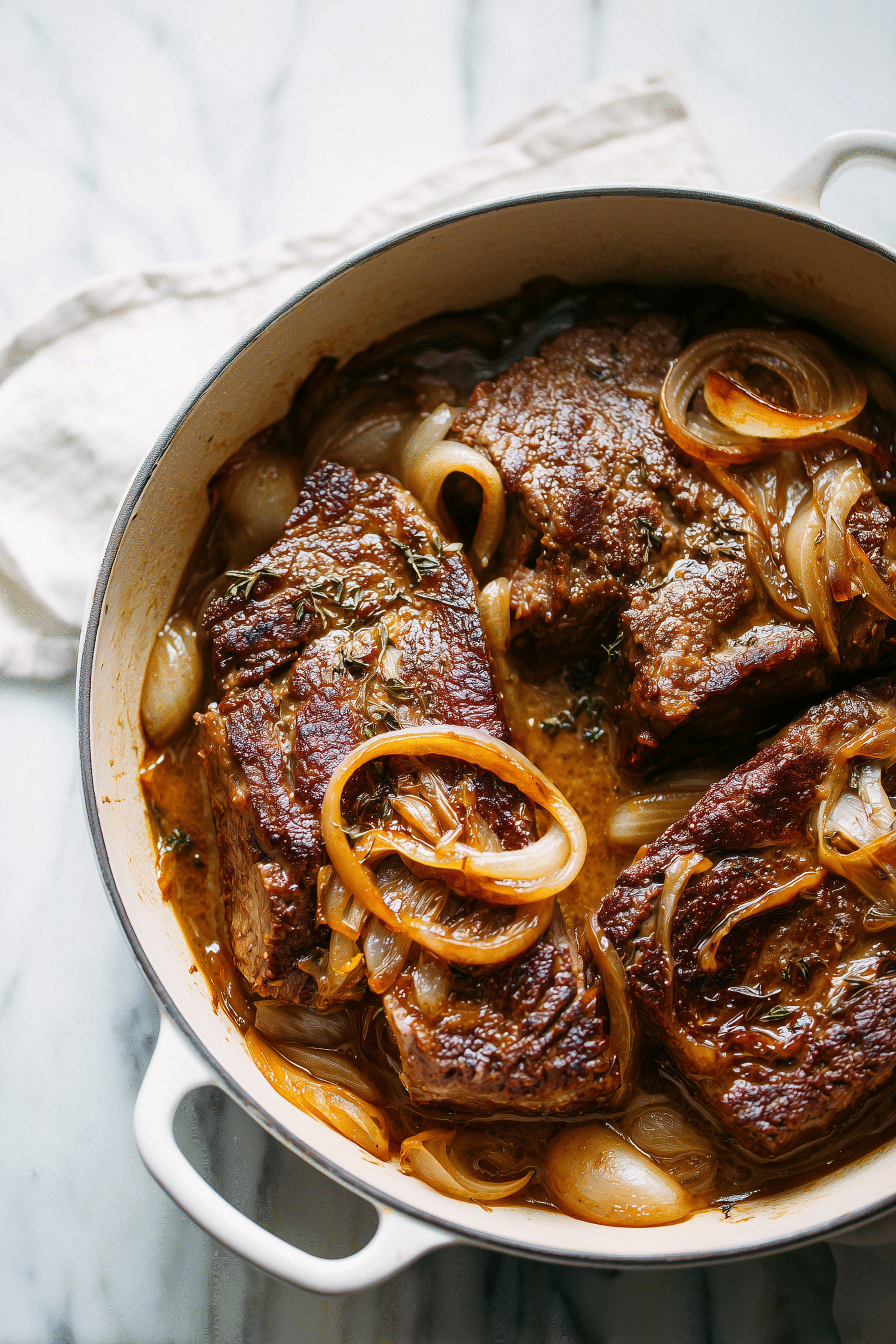 Close-up of Slow Cooker French Onion Pot Roast with caramelized onions and beef in a Dutch oven.