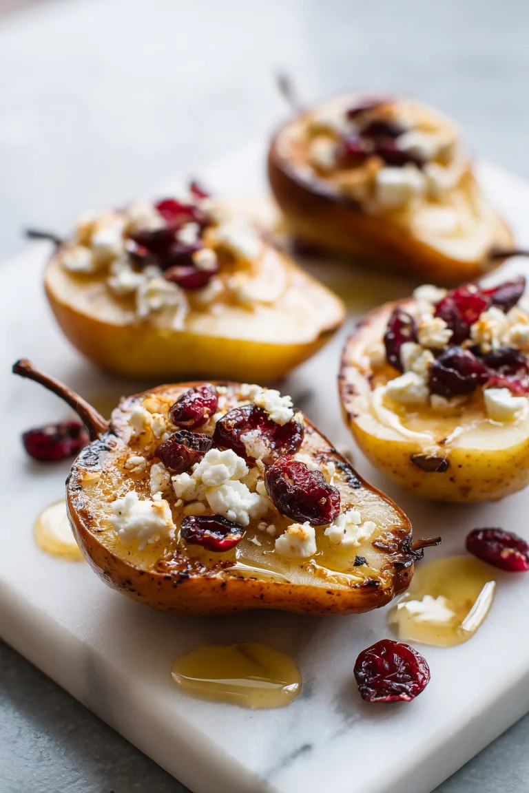 Baked Pears Feta Honey Cranberries arranged on a marble dish with glistening honey and feta.