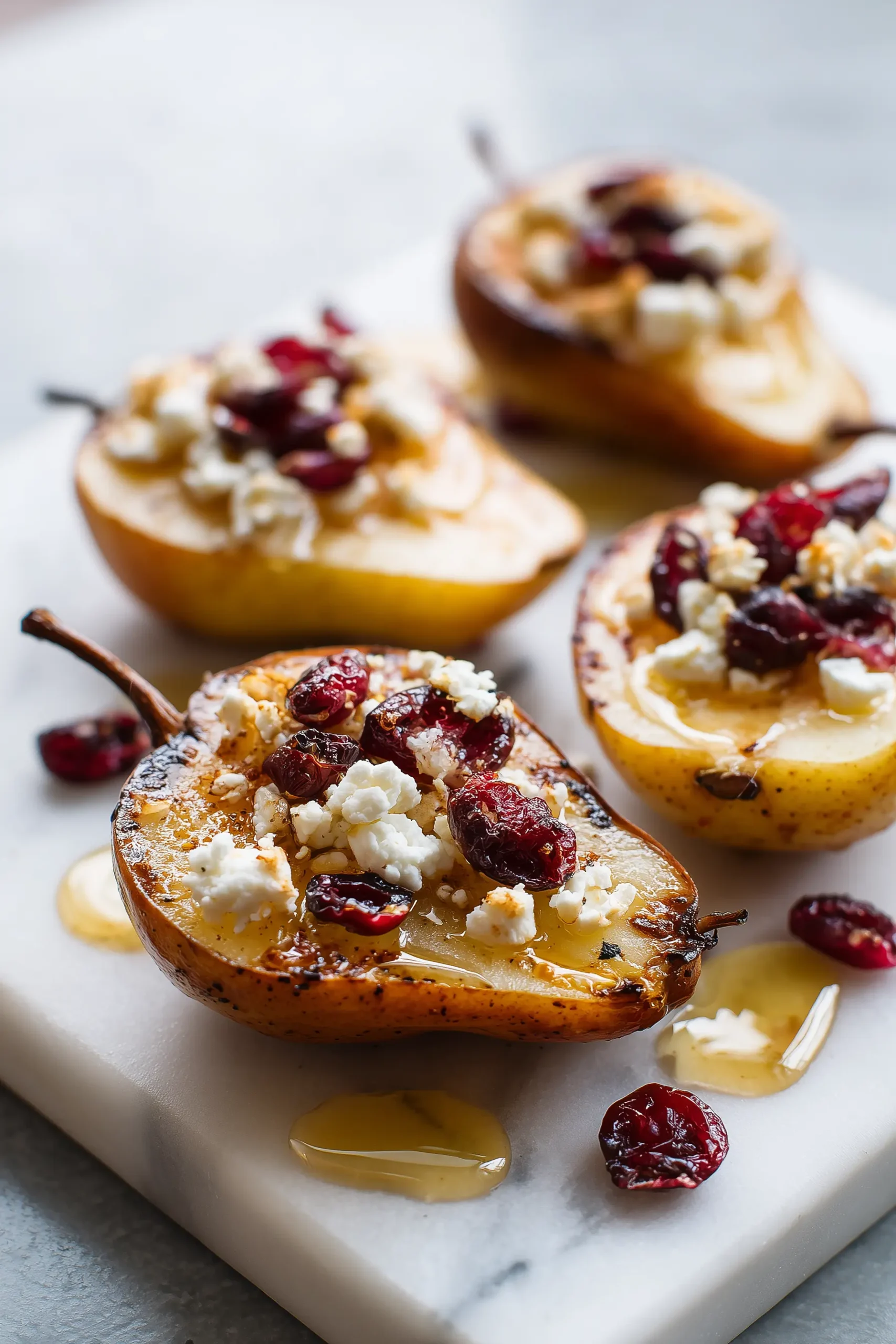 Baked Pears Feta Honey Cranberries arranged on a marble dish with glistening honey and feta.