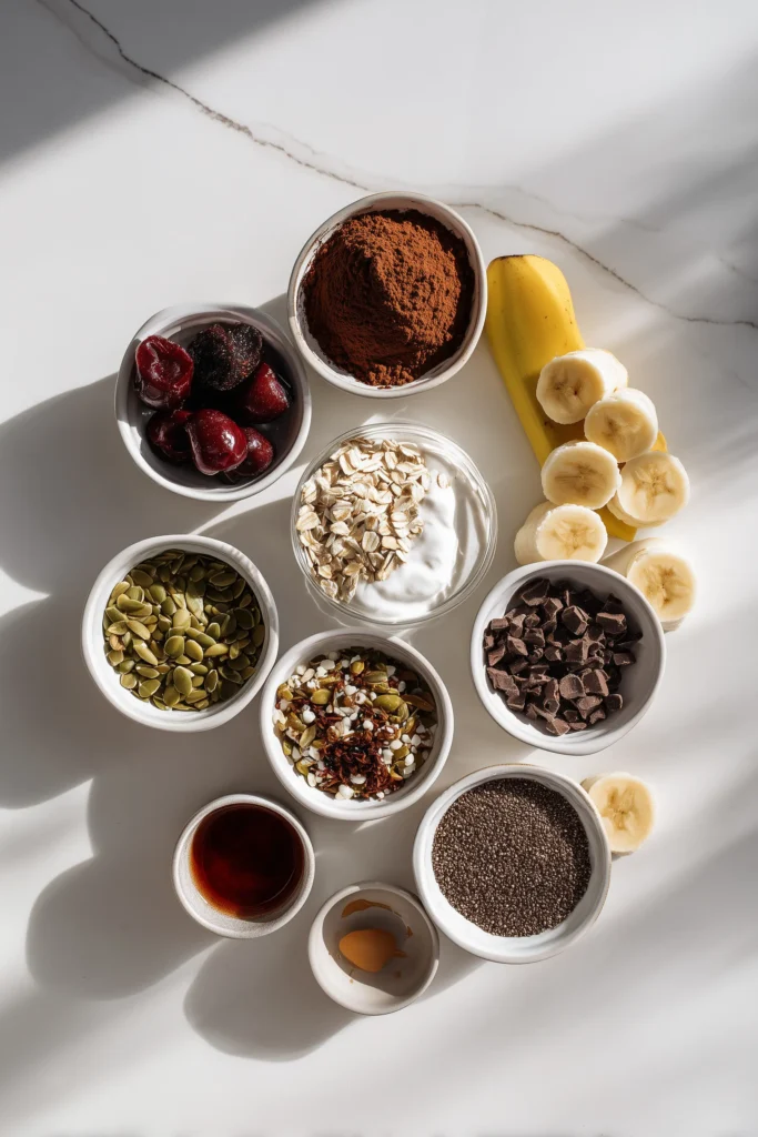 An overhead shot of Black Forest Creamy Oats ingredients, including oats, cherries, cocoa, yogurt, and more.
