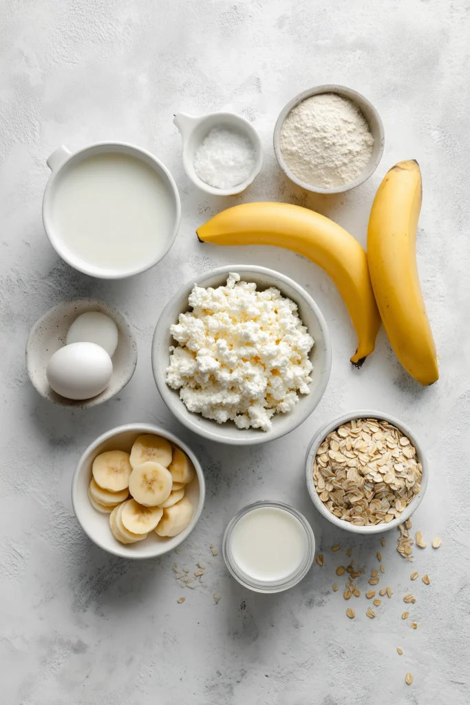 Cottage cheese, oats, eggs, banana, and pancake ingredients laid out for Cottage Cheese Protein Pancakes.