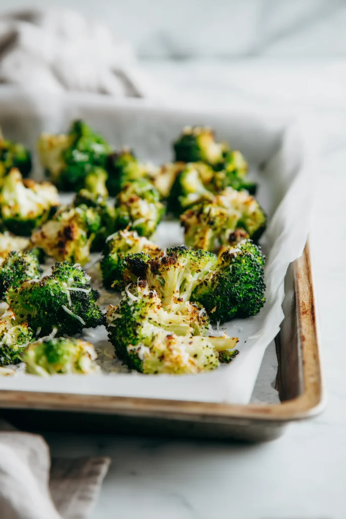 Cozy Thanksgiving Broccoli Side Dish (Crispy, Creamy & Crowd-Pleasing) 3 Roasted Thanksgiving Broccoli Side Dish just out of the oven, golden and topped with melted Parmesan on a baking sheet.
