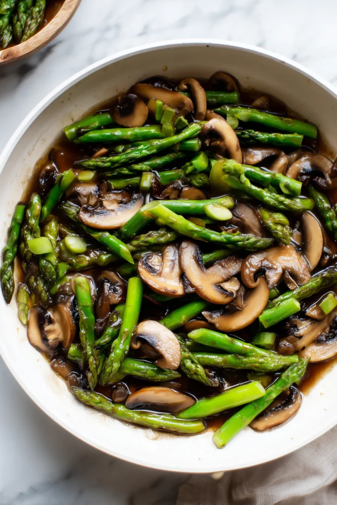 Savory Asparagus and Mushrooms Stir-Fry 3 Close-up of savory asparagus and mushrooms stir-fry sizzling in a white skillet.