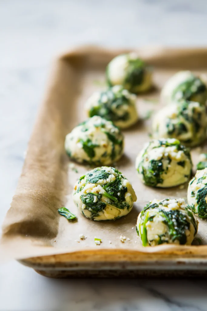 Several unbaked 5 Irresistible Cottage Cheese Flagels on a parchment-lined baking sheet, ready for the oven.
