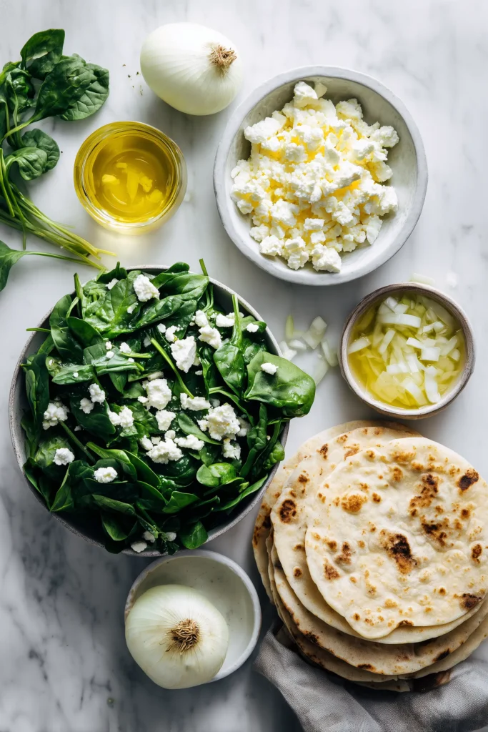 Crustless Spinach Onion Feta Tortilla 2 Ingredients for Crustless Spinach Onion Feta Tortilla neatly arranged on a white marble background.