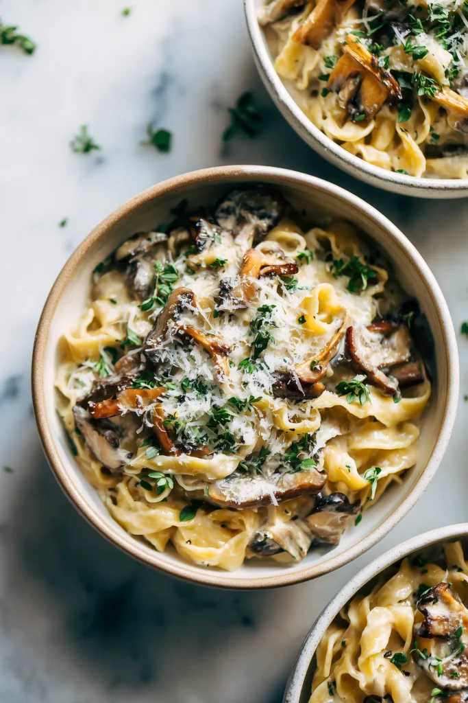 Garlic Butter One Pot Mushroom Parmesan Pasta 3 Creamy Garlic Butter One Pot Mushroom Parmesan Pasta served in bowls, topped with parmesan and herbs.