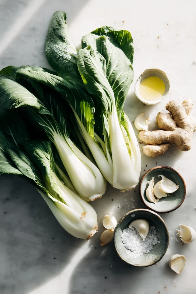 Garlic Ginger Bok Choy 2 Overhead image of fresh bok choy, ginger, garlic, oil, and salt for Garlic Ginger Bok Choy on a marble background.