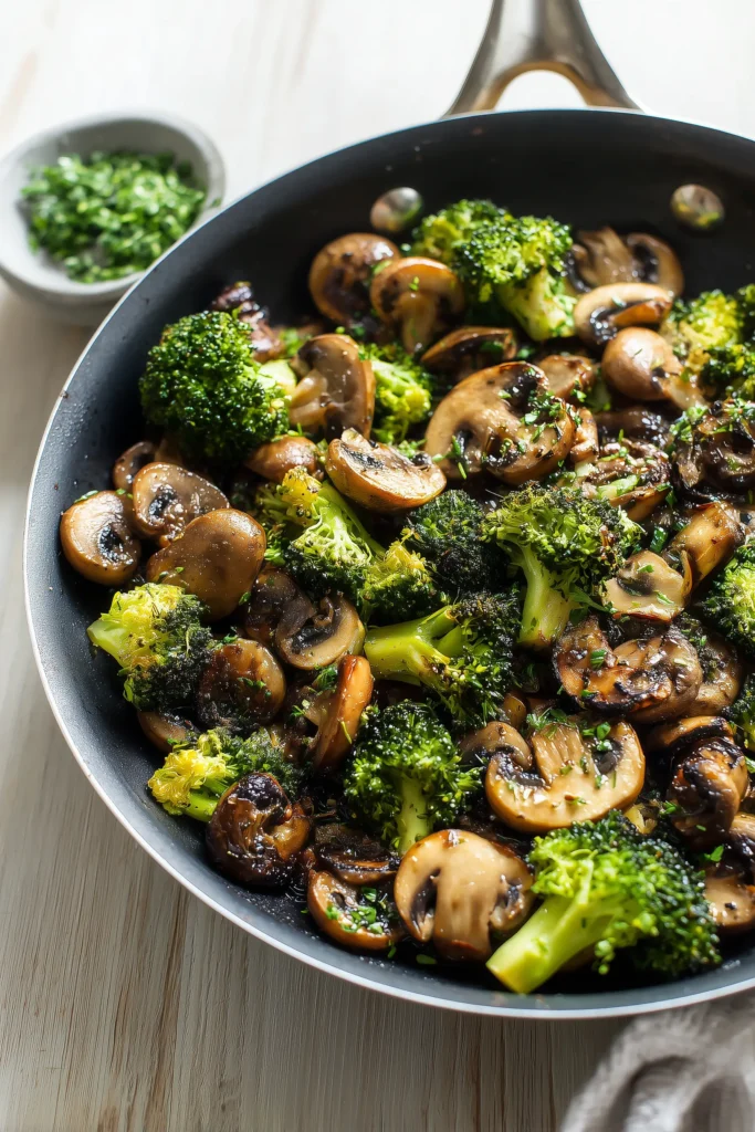 Overhead of sauteed mushrooms with broccoli in a skillet, mushrooms golden brown and broccoli fresh green.