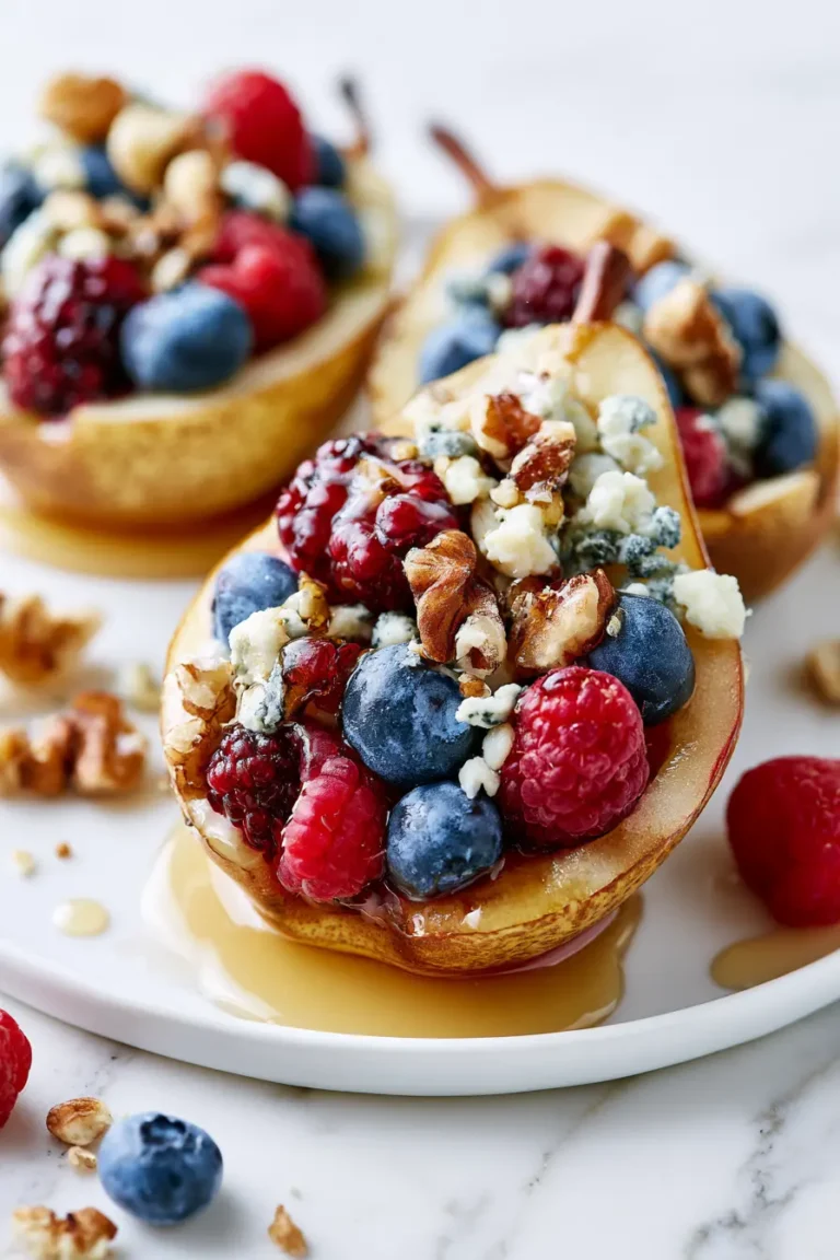Hero image of Baked Pears with Berries, Honey, Walnuts & Blue Cheese served on a white plate over white marble, drizzled with honey and topped with berries and walnuts.